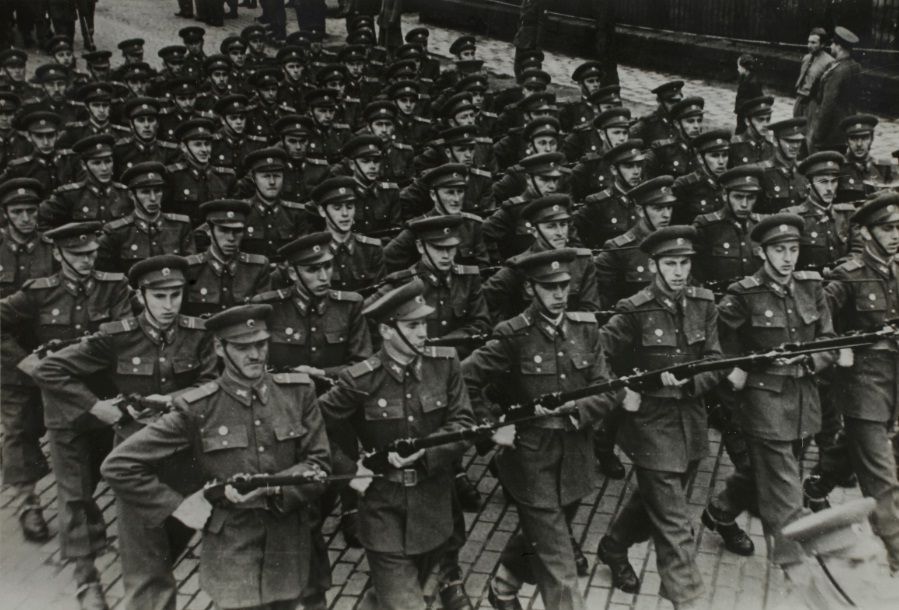 Guardsmen of the ÁVH marching in uniform holding rifles.